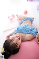 A little girl laying on a pink pillow with balloons.