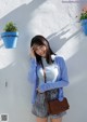 A woman standing in front of a white wall talking on a cell phone.