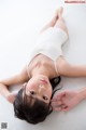 A woman in a white leotard laying on the floor.