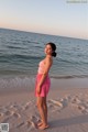 A woman standing on a beach next to the ocean.