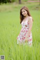 A woman in a white dress standing in a field of tall grass.