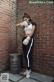 A woman wearing boxing gloves leaning against a brick wall.