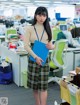 A woman in a plaid skirt holding a blue folder.