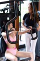 A woman in a pink bikini sitting on a gym machine.