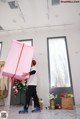 A man carrying a large pink box in a room.