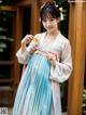 A woman in a blue and pink hanbok holding a spoon.