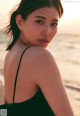 A woman in a black bathing suit sitting on the beach.