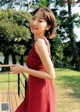 A woman in a red dress standing on a wooden deck.