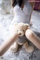 A woman sitting on a bed holding a teddy bear.