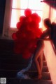 A naked woman holding a bunch of red balloons.