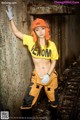 A woman in a yellow shirt and orange hard hat posing for a picture.