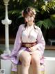 A woman in a pink kimono sitting on a white bench.