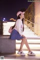 A woman sitting on the steps of a building at night.