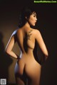 A nude woman with a tattoo on her back.