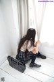 A woman sitting on the floor next to a window.