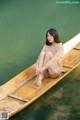 A woman sitting on a wooden boat in the water.